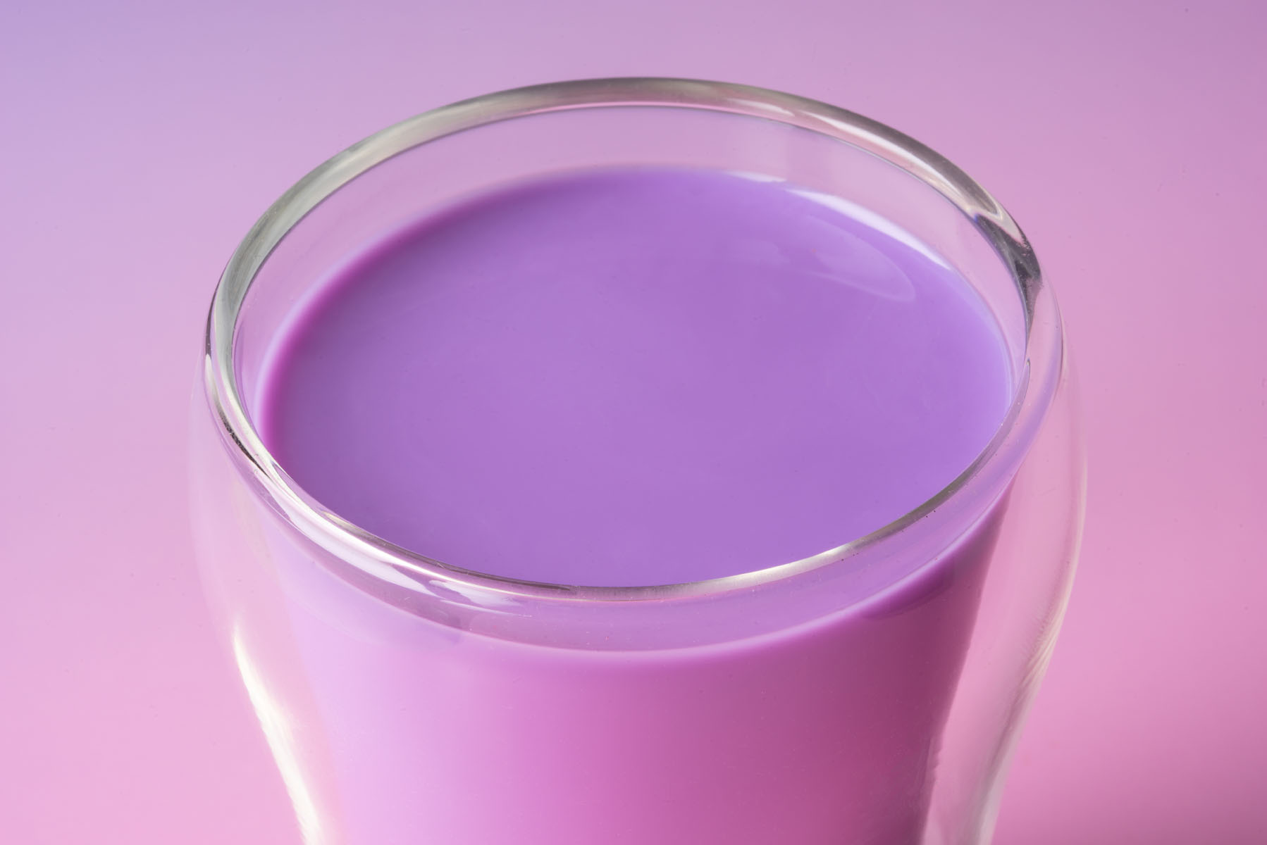 Glas Ube Latte in Nahaufnahme vor violettem Hintergrund