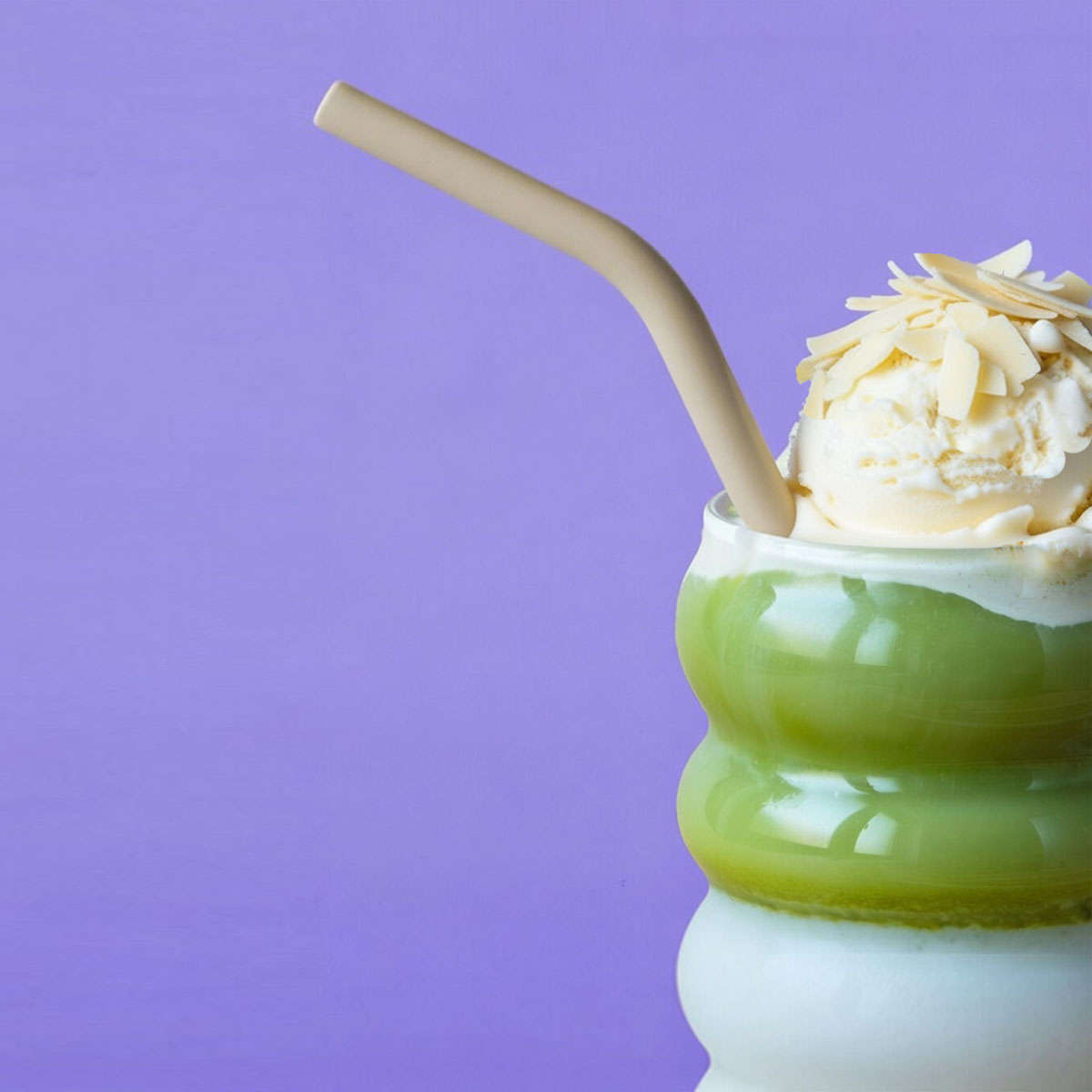 Vanille-Matcha-Getränk mit Sahnehaube und Strohhalm vor violettem Hintergrund